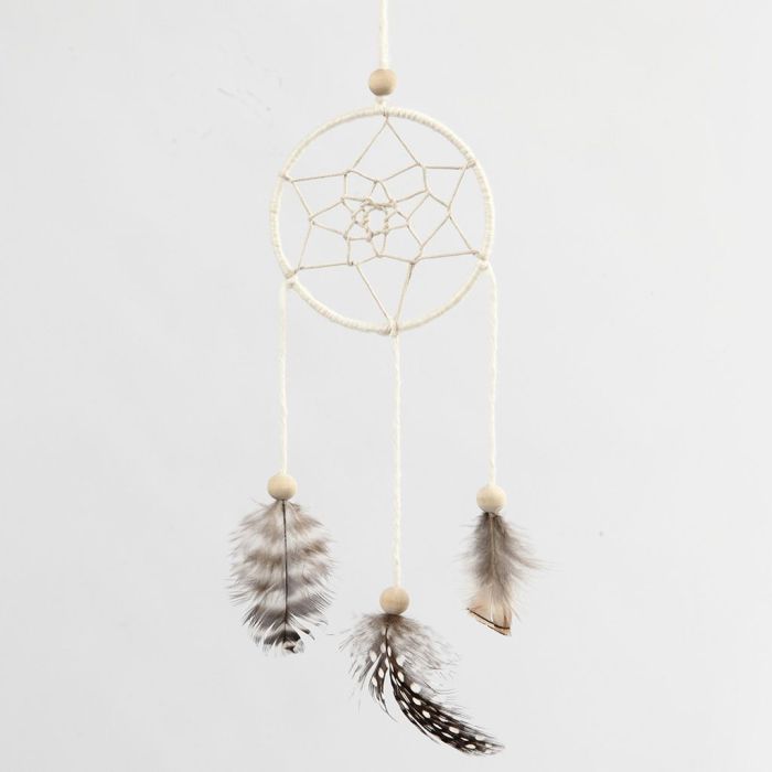 Un attrape-rêves réalisé avec un anneau en métal enroulé de fil de coton, de cordon de coton ciré et décoré de plumes
