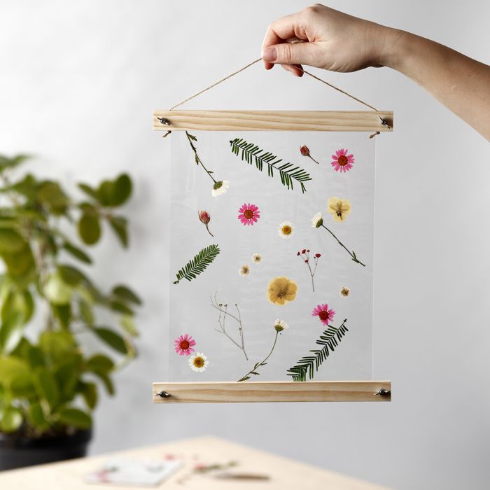 Une décoration suspendue avec des fleurs séchées et laminées dans des supports d’affiche