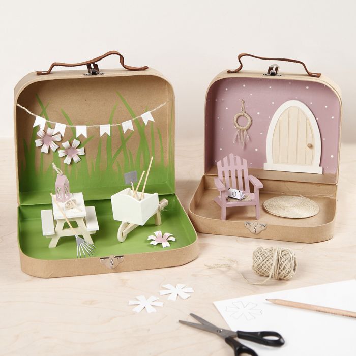 Petites valises transformées en monde de jardin avec de la peinture, des meubles miniatures et des accessoires.