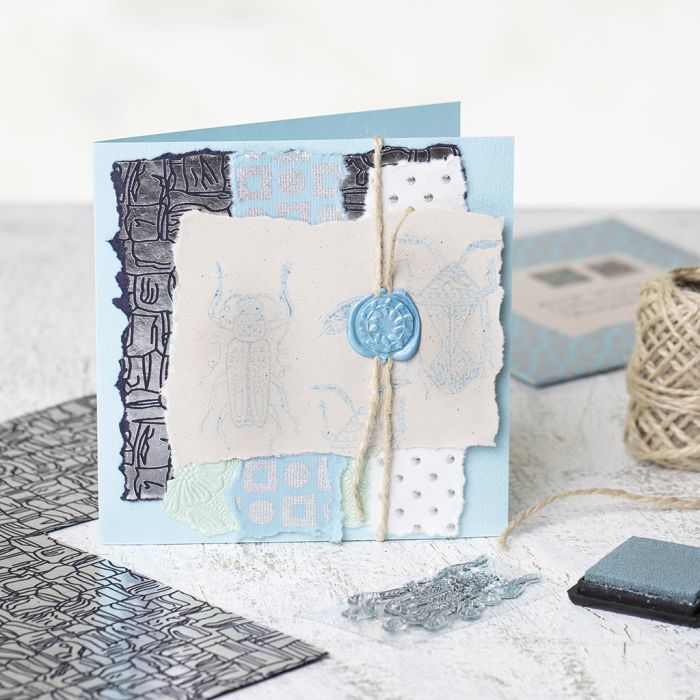 Une carte de vœux faite maison avec du papier artisanal, des motifs estampés et un sceau de cire.