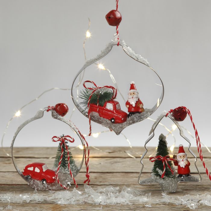 Décorations de Noël suspendues avec des figurines miniatures dans des emporte-pièces de formes.