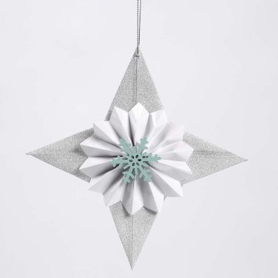 Une étoile en papier pailleté décorée avec une rosette et un flocon de neige