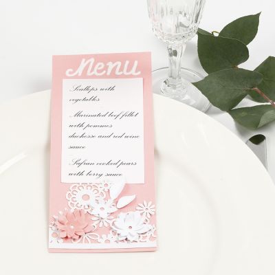Une carte de menu avec une carte à motif de dentelle et des fleurs découpées à l’emporte-pièce.