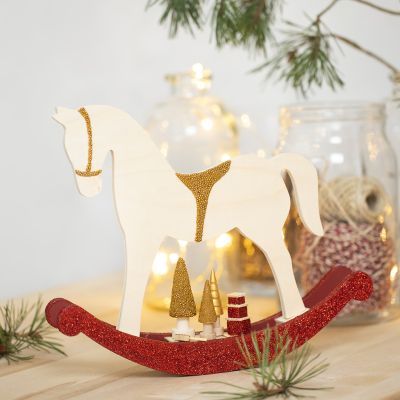 Un cheval à bascule avec de petits accessoires en bois décorés avec de la peinture de loisir créatif