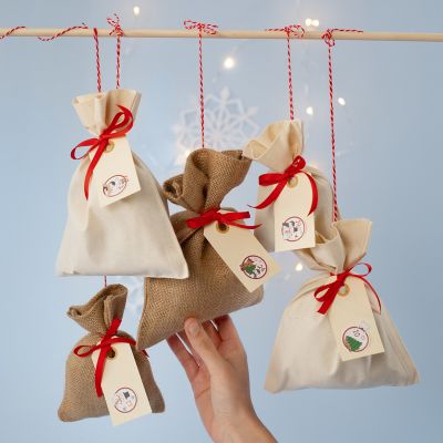 Un calendrier de l’Avent composé de sacs en tissu avec une étiquette en papier kraft numérotée.