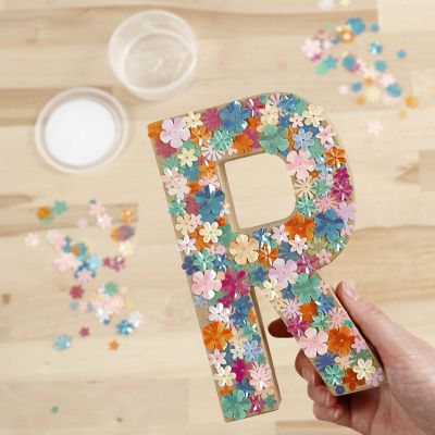 Une lettre en papier mâché décorée de paillettes et de Sticky Base.