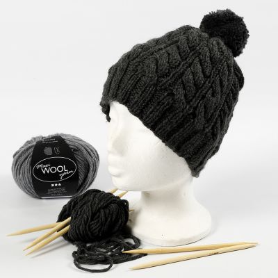 Un bonnet tricoté avec un motif torsadé et un pompon.