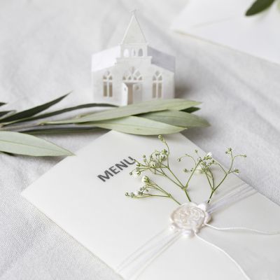 Une carte de menu dans des tons ivoire avec une église perforée et du papier calque