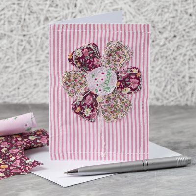 Une carte de vœux avec un motif de fleur en tissu cousu.
