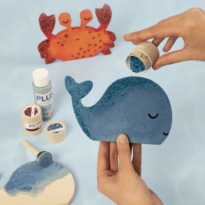 Une baleine et un crabe décorés avec de la peinture de loisirs créatifs et des paillettes biodégradables.